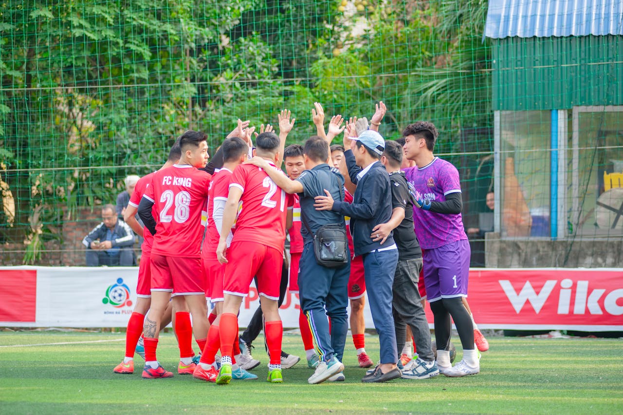 Soccer team huddling on the field during a daytime match in Hà Nội, Vietnam.